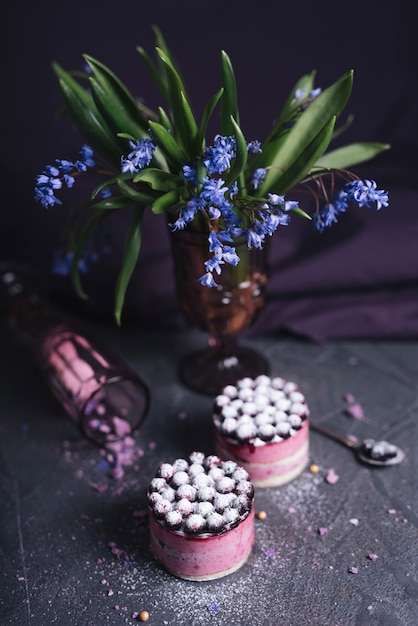 Free photo purple flower vase with two delicious cheese cake on rock textured background