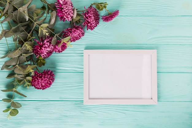 Free Photo purple flowers with blank frame on blue wooden table