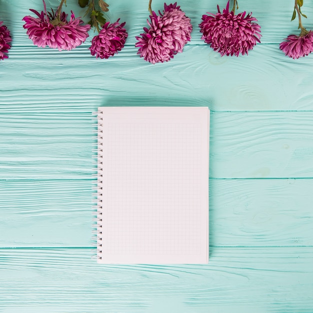 Free photo purple flowers with blank notebook on blue table