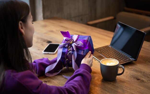 Purple gift box in a womans hands in a purple sweater