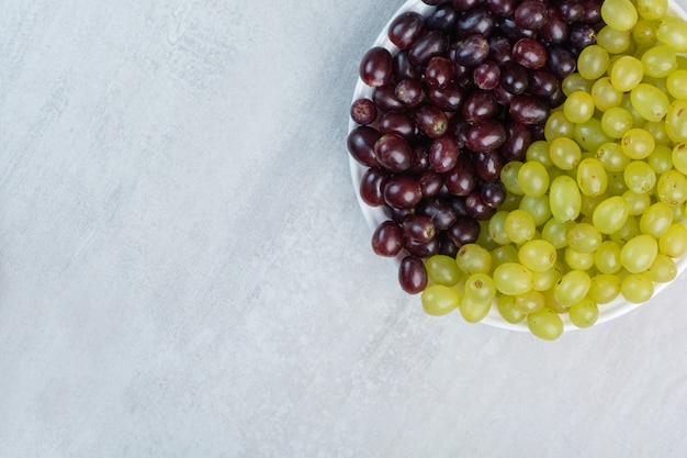 Free photo purple and green grapes on white plate