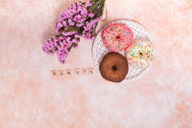 Free Photo purple gypsophila flowers; donuts blocks and baked donuts on plate over the rustic backdrop