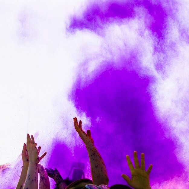 Purple holi color over the people raising their hand dancing