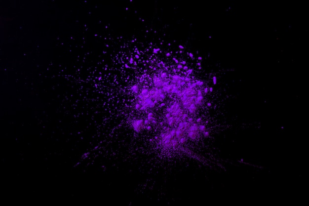 Free photo purple indian festival color particles on dark black surface