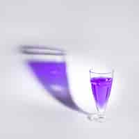 Free photo purple liquid in the single glass with shadow over white backdrop