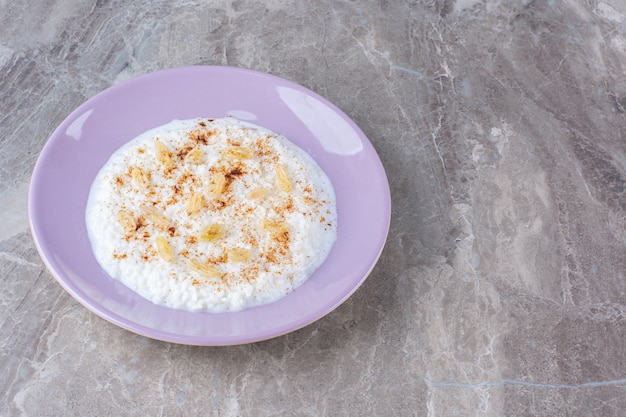 A purple plate full of healthy oatmeal porridge with cinnamon powder . 