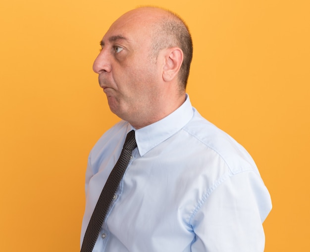 Pursing lips middle-aged man wearing white t-shirt with tie isolated on orange wall