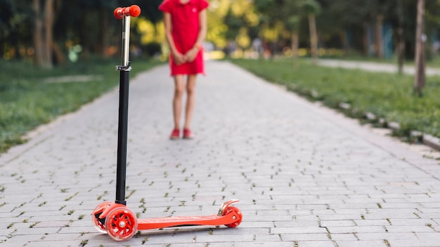 Push scooter in front of girl standing on walkway in the park