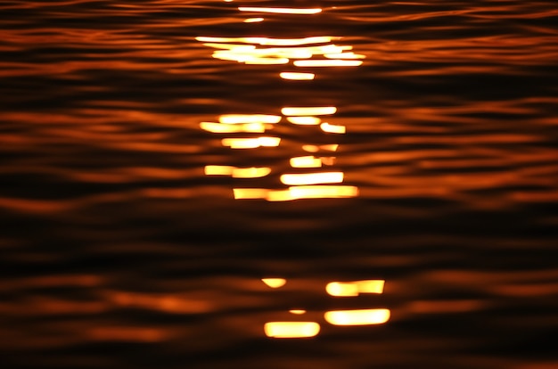 Free photo put of focus shot of sea waves reflecting the sun at sunset