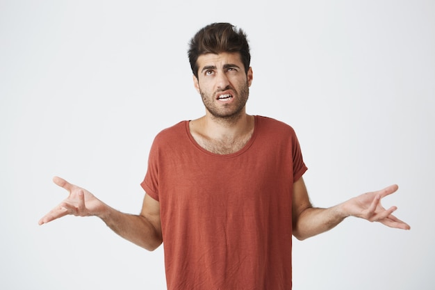 Free photo puzzled and clueless bearded man with stylish hairstyle dressed in casual clothing shrugging shoulders and staring with confused look after he made mistake but not feeling guilty for that