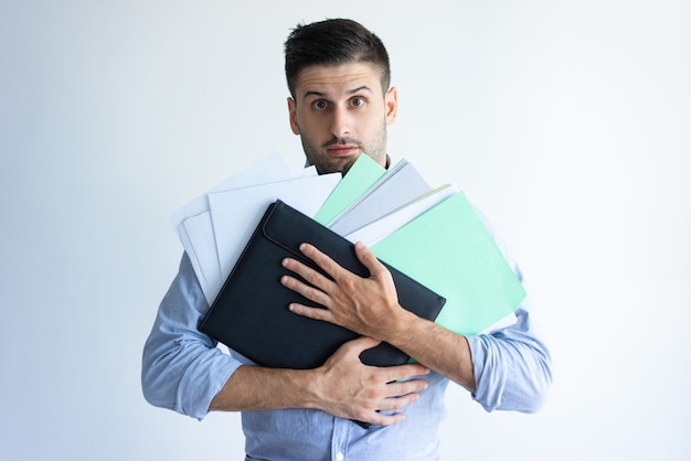 Free photo puzzled office worker holding pile of documents