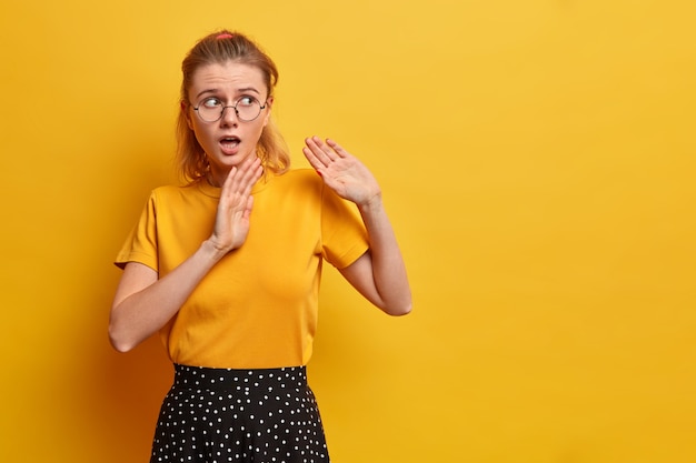 Free photo puzzled scared european girl keeps palms forward asks not to come close says stay away from me afraids of something