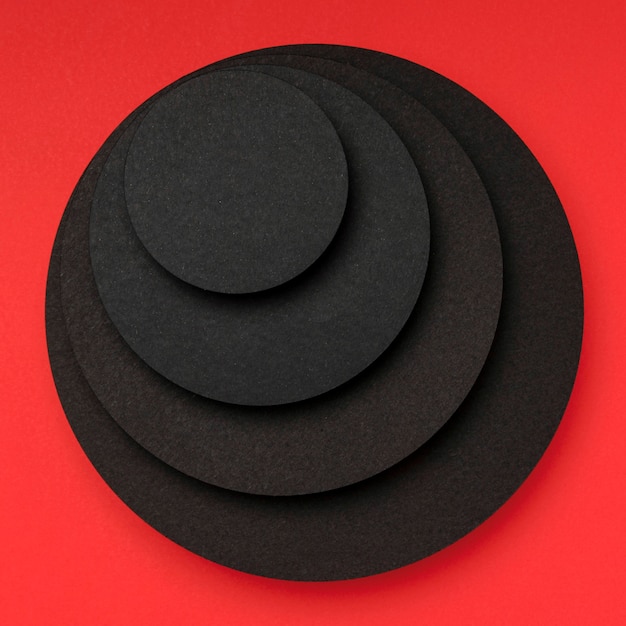 Free photo pyramid of circular pieces of black paper on red background