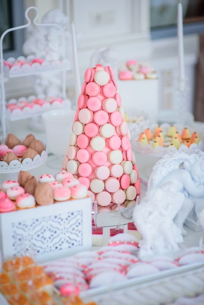 Free photo pyramid of pink and white macaroons stands on candy bar