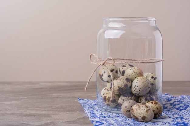 Quail eggs in a jar container on the blue towel