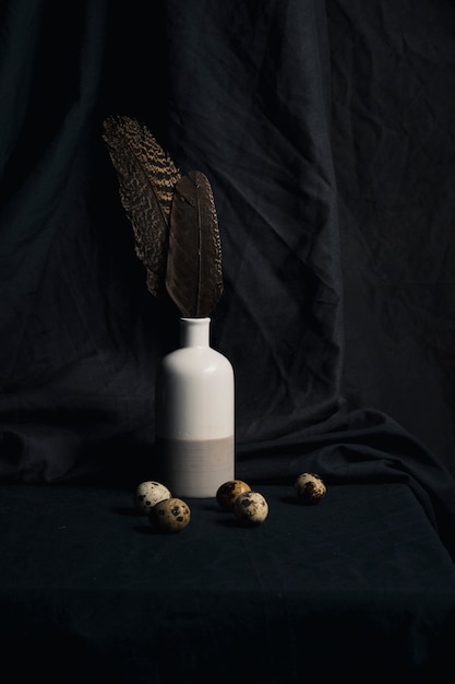 Quail eggs near feathers in vase