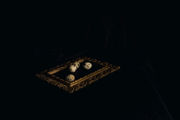 Free Photo quail eggs on photo frame between blackness