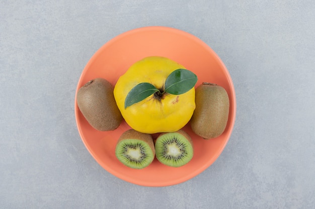 Quince and sliced kiwis on orange plate