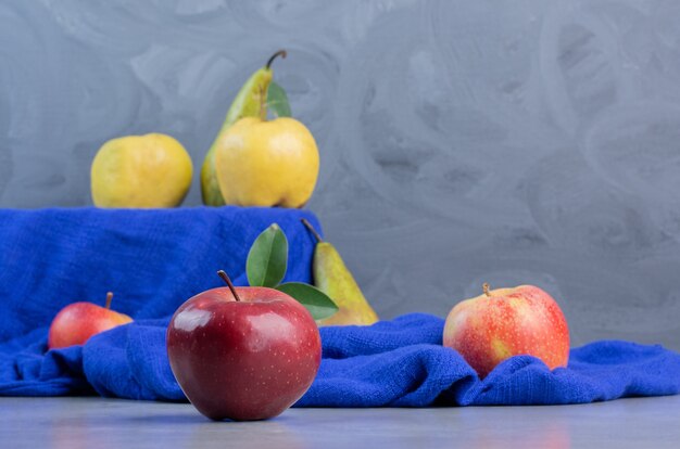 Free photo quinces, apples and pears on blue tablecloth on marble background.