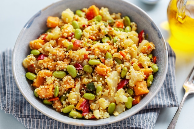 Quinoa with vegetables cooked for lunch or dinner and served in bowl. Closeup.