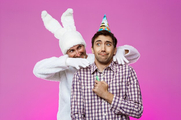 Rabbit frightening drunk man over purple wall. Birthday party.