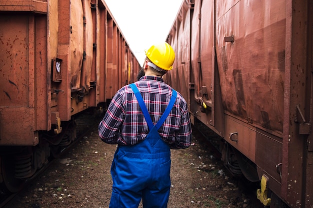 Free Photo railroad supervisor walking between train wagons and checking cargo for shipping companies