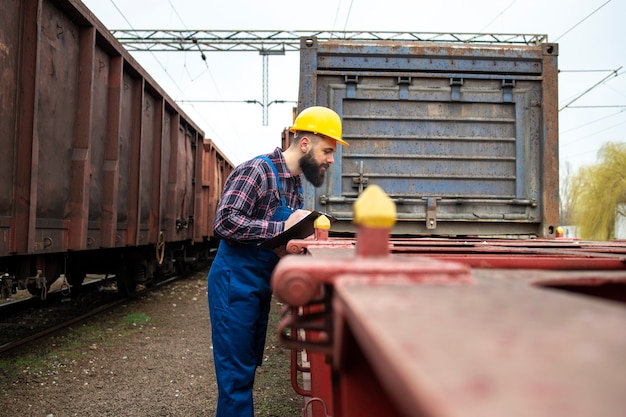 Free photo railroad worker checking train cars at the station