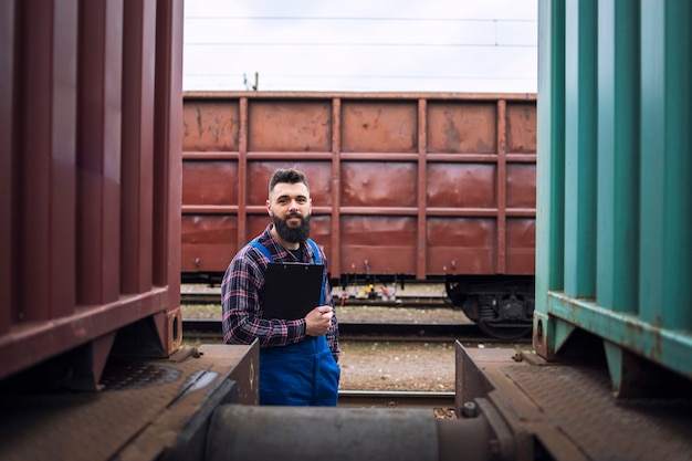 Free Photo railroad worker standing by trains and looking to the camera at the station