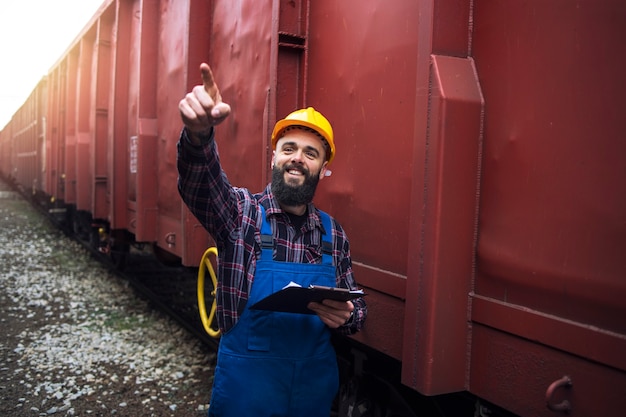 Free Photo railroad worker supervisor checking cargo and pointing to one of the freight train cars