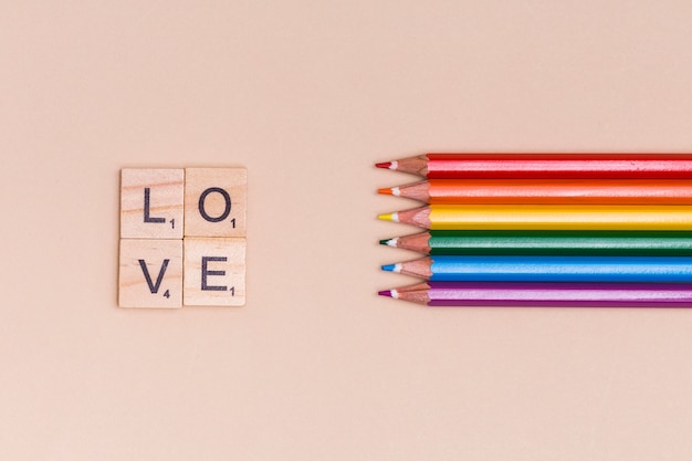 Free photo rainbow colorful pencils and love letters on beige background