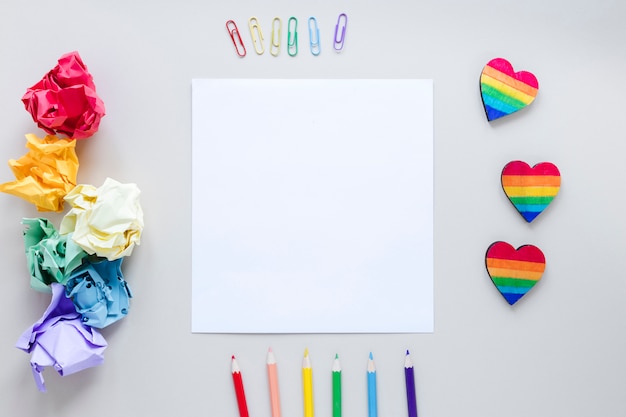 Free photo rainbow hearts with paper and pencils