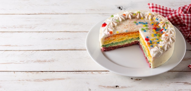 Rainbow layer cake on white wooden table