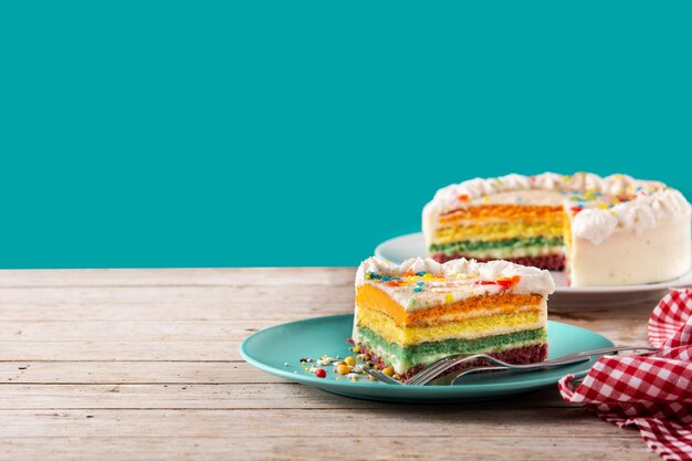 Rainbow layer cake on wooden table and blue background