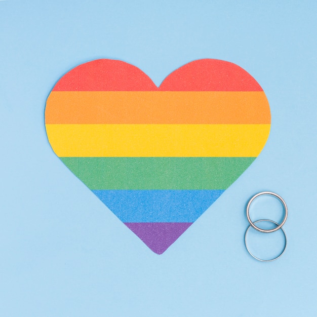 Free Photo rainbow lgbt heart and wedding rings on blue background