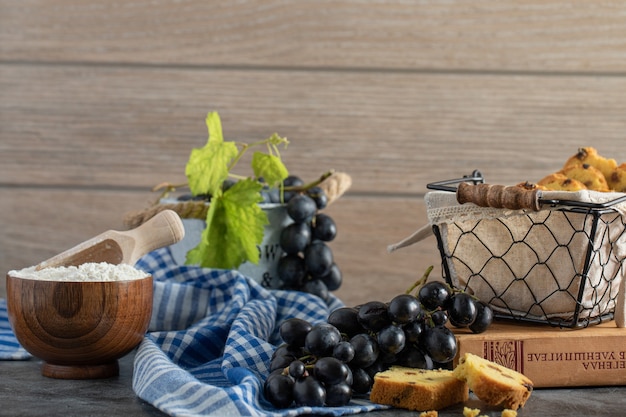 Free photo raisin cake, grapes and bowl on flour on marble table