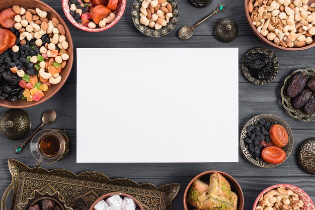 Ramadan card surrounded with traditional dried fruits; dates; tea and baklava on table