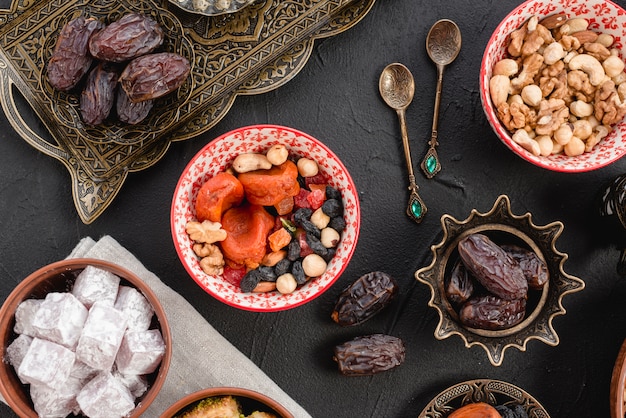 Free photo ramadan juicy dates and dried fruits; nuts and lukum on black background