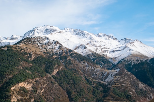 Range of high rocky mountains covered with snow under the cloudy sky