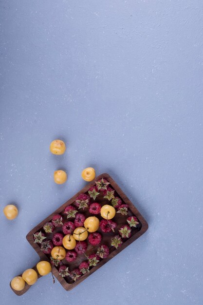 Raspberries and cherries in a wooden platter on the bottom side