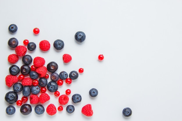 Raspberries with blueberries, redcurrants top view on a white background