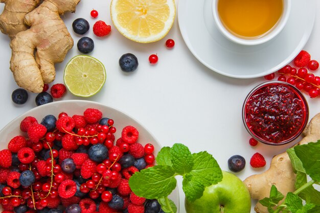 Raspberries with lemon, mint leaves, jam, blueberries apple, ginger top view