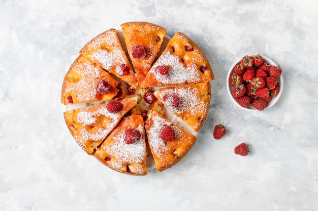 Raspberry cake with powdered sugar and fresh raspberries on a light . Summer berry dessert.