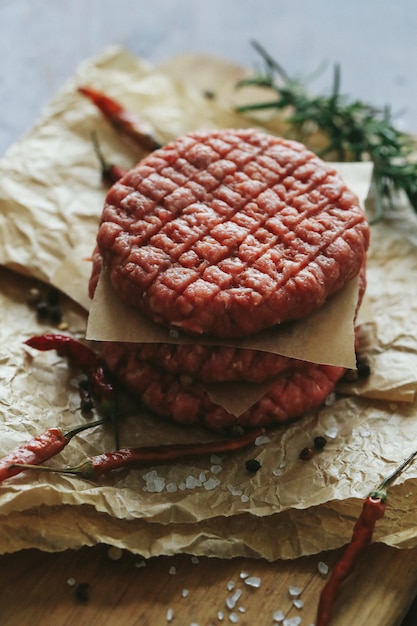 Free photo raw beef hamburger patties with herbs and spices on dark slate plate