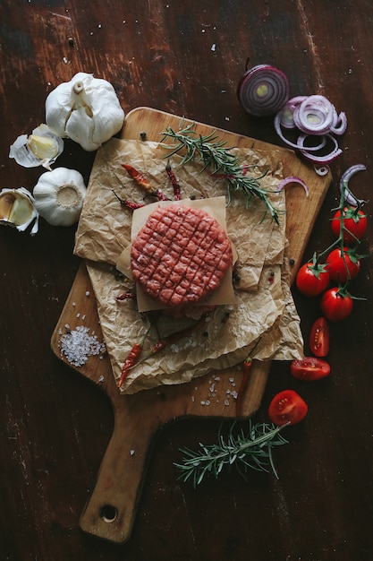 Free photo raw beef hamburger patties with herbs and spices on dark slate plate