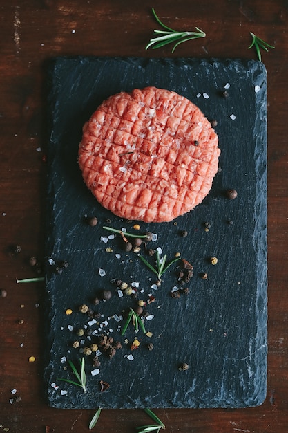 Raw beef hamburger patties with herbs and spices