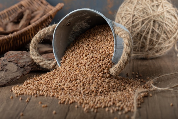 Raw buckwheat out of metal bucket on wooden table