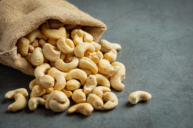 Raw cashews nuts in bag on dark background