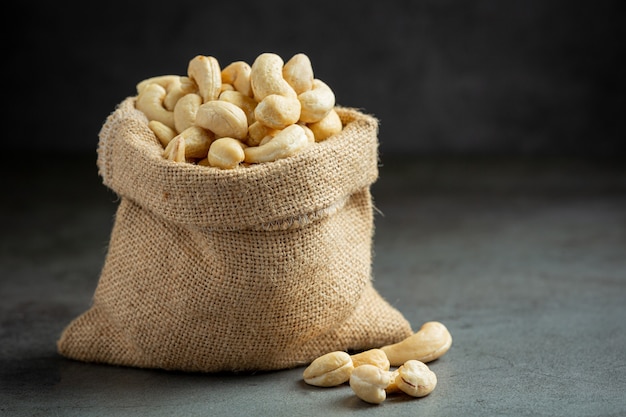 Raw cashews nuts in bag on dark background