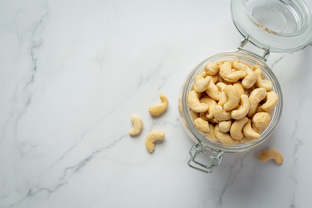 Free photo raw cashews nuts in an open glass jar on marble background