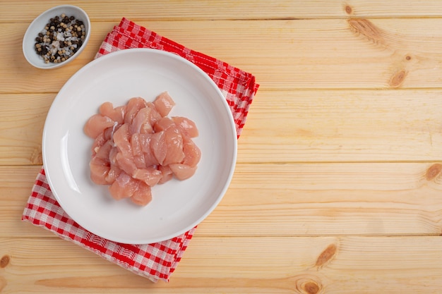 Raw chicken breast on the wooden surface.